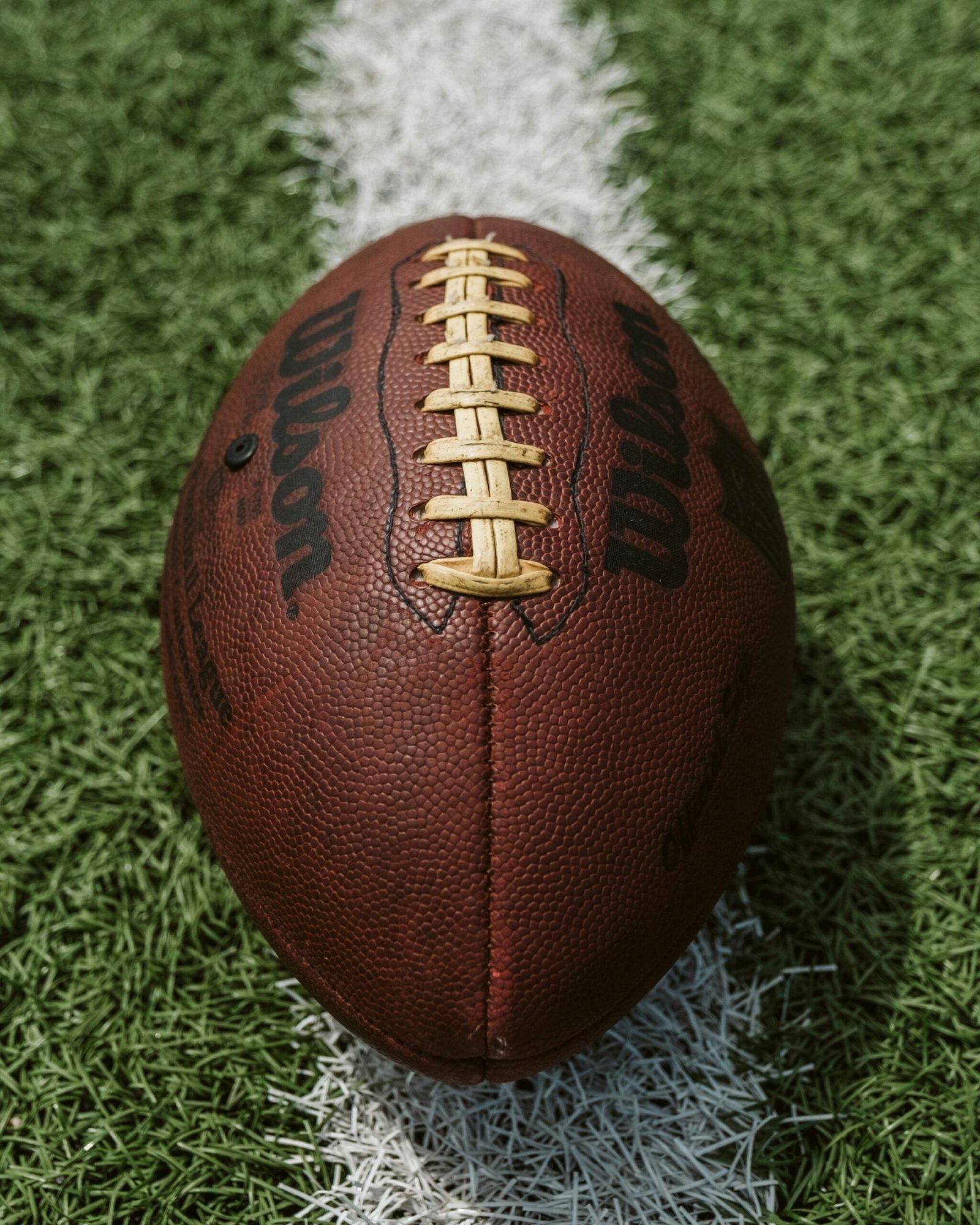Close-up of a brown American football centered on white field markings